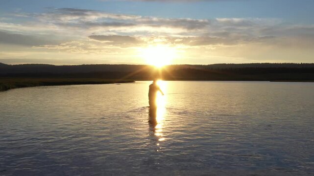 Fisherman Silhouette Casting in River During Golden Sunset