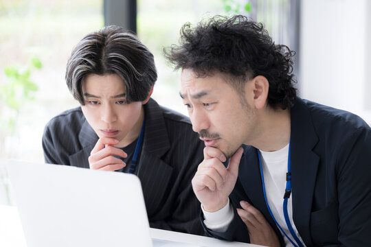 問題を検討する上司と若手社員の思考と解決のビジネスシーン どうしようか悩む迷う考えるの顎に手を当てるポーズ