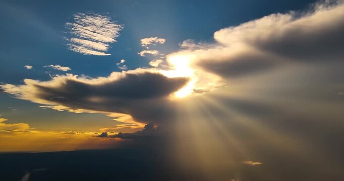 Aerial view of golden sun rays piercing through dramatic storm clouds