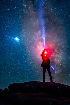 Silhouette of a man on a rock holding a lamp on a dark, starry night with the Milky Way in the background, in Mexiquillo, Durango 