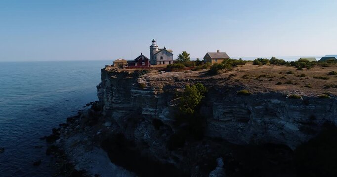 Drone flying toward lighthouse on limestone cliffs of Stora Karls&ouml;, Gotland, Sweden overlooking the Baltic Sea