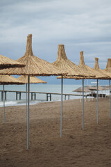 Fototapeta premium Beach umbrellas stand at seaside during cloudy day