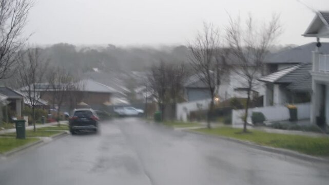 Rain blurred suburban street view through car window on a gloomy day in Doreen, Melbourne Australia. Melancholic atmosphere &mdash; rain, limited visibility and reflective mood in local neighborhood