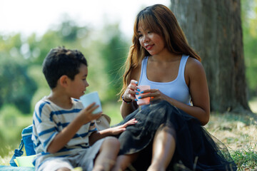 Obraz premium Mother and son enjoying a picnic outdoors in a serene park setting together