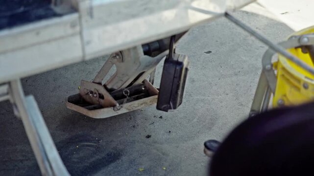 A worker winding up a stabiliser leg on a mobile coffee cart, retracting the support before moving, closeup. Early morning industrial setup with practical hands-on workflow.