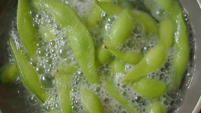 Cooking edamame beans in boiling water for a healthy snack