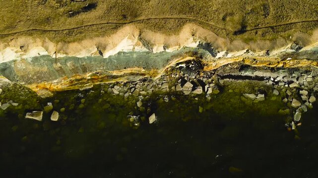 Beautiful aerial footage flying over the pakri cliff bank on the baltic sea coast, revealing a dramatic shoreline, layered rock formations, and a large wind farm generating renewable energy