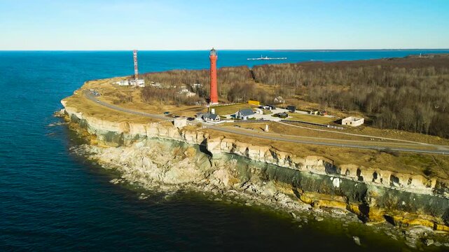 Picturesque aerial view of the historic red pakri lighthouse standing on a dramatic limestone cliff overlooking the baltic sea on a sunny spring day in paldiski, estonia