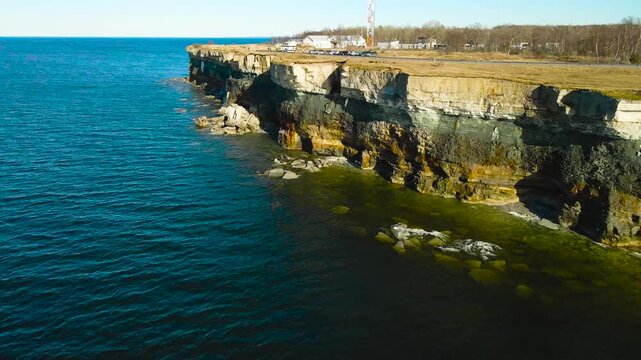 Majestic aerial footage capturing the stunning limestone cliffs of the pakri peninsula in estonia, showcasing the rugged coastline meeting the deep blue waters of the baltic sea on a sunny day