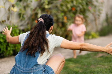 Obraz premium Mother Embracing Child Running Outdoors in a Sunny Garden