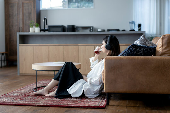 ヘッドフォンをしてホットドリンクを飲む若い日本人女性
