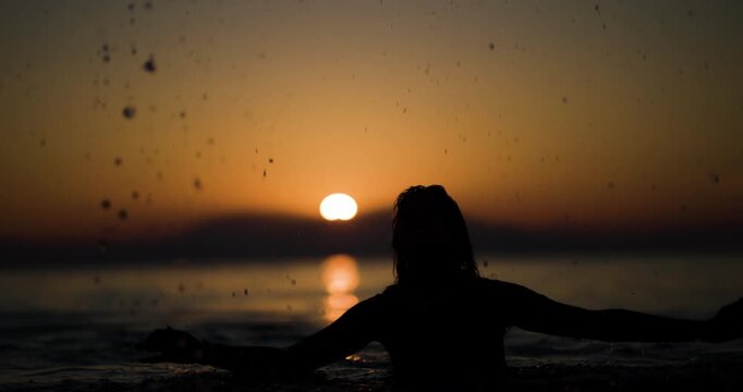 Sunset silhouette of a person by the sea, enjoying the tranquil beauty of water as the sun dips below the horizon