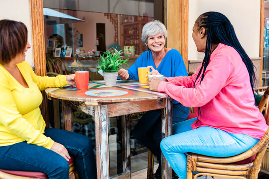 Multiracial senior friends having fun outside cafe bar restaurant - Focus on grey hair woman - ugc content