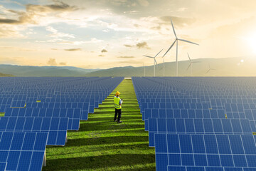 Engineer standing in solar farm and wind turbines for energy transition