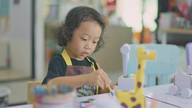 Young child learning painting while decorating a plaster figurine with a brush, developing artistic skills, creativity, concentration, imagination.