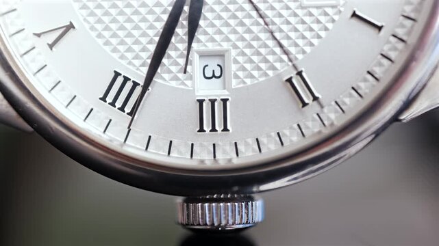 Close up of elegant watch face with roman numerals and date window ticking showing time passing.