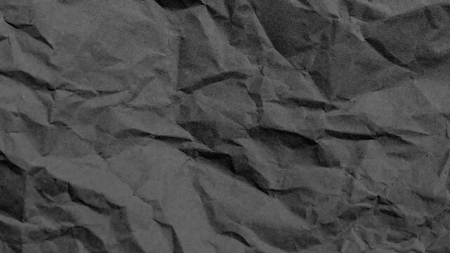 Crumpled black paper texture background, wrinkled charcoal parchment surface, dark textured paper overlay for cinematic video editing