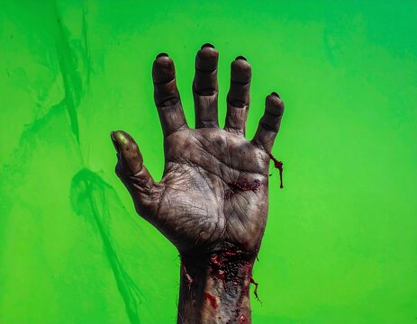 A zombie's bloody hand raised against a green background