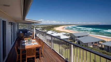 Fototapeta premium Elevated wooden deck overlooks expansive sandy beach and turquoise ocean water under clear blue sky
