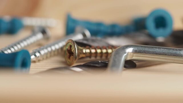 Macro view of assorted hardware including screws wall plugs and hex keys on wooden surface.