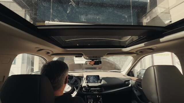 POV footage Driver inside vehicle entering automatic car wash with visible interior view and glass roof.