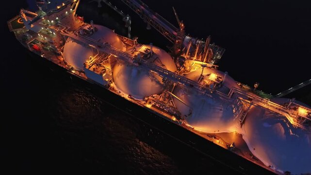 Aerial of Liquified Natural Gas LNG carrier moored to a small gas terminal at night. Fuel crisis. Sanctions