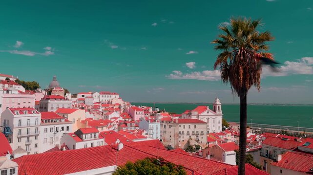 Panoramic view over Lisbon&rsquo;s Alfama district with terracotta rooftops, S&atilde;o Vicente de Fora, the National Pantheon, and the Tagus River under a bright blue summer sky.
