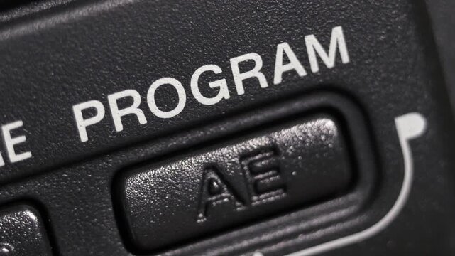 Diagonal macro of Program AE on dark grey plastic with white lettering