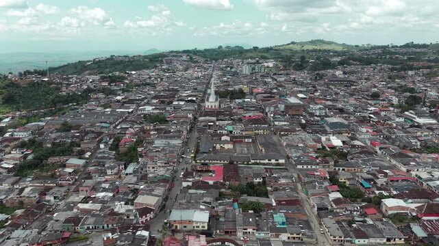 Drone video capturing a sweeping aerial view of the picturesque cityscape of Sevilla in Valle del Cauca, Colombia. The video showcases the densely packed urban area against a sprawling landscape.