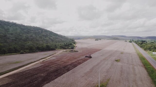 Tractor with precision planter operating across prepared and planted soil in Formosa, Goi&aacute;s, Brazil, showing large-scale agribusiness seeding, row geometry and cerrado landscape transition, drone push
