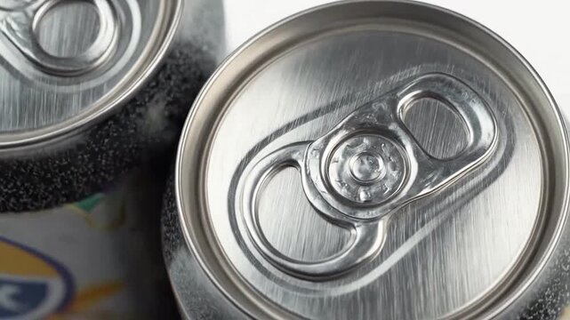 Two metallic beverage containers with pull tabs are shown up close