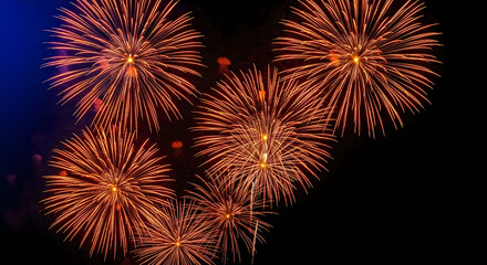 Obraz premium Brilliant orange fireworks explode against a dark deep blue night sky