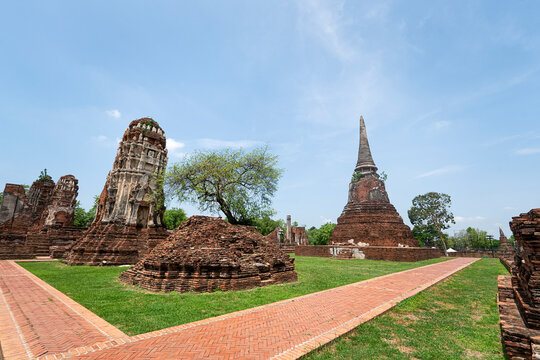 Old brick pagoda in ancient temple in Ayutthaya, old capital city of Thailand, UNESCO World heritage place, under cloudy blue sky in summer