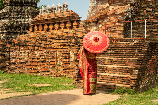 asian woman wearing thai traditional suit stand with umbrella against old temple in ayutthaya world heritage of unesco thailand