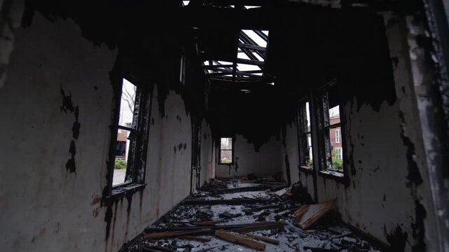 Charred brick window revealing gutted interior, collapsed roof and scorched beams, sootcoated plaster, debrisstrewn floor, dim light through broken frames,