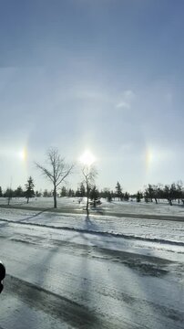 Driving through a stunning Sun Dog and solar halo in winter. Close-up of rare atmospheric phenomenon and frozen trees from a moving car in Regina, Saskatchewan.