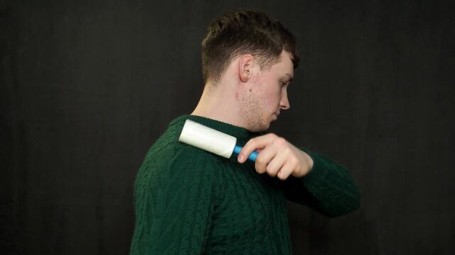 Man cleaning clothes with lint roller at home, closeup