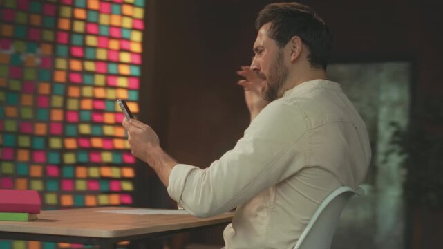Animated individual in snug studio wearing expressive gestures while engaging with mobile device and sharing laughter