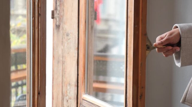 Woman hand opens and closes wooden window, a close-up cinematic shot of home interior, natural daylight, light color, smooth motion footage.