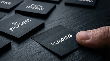 Fototapeta premium Strategizing Business Processes Hand Placing 'Planning' Tile on a Dark Textured Board Amidst Workflow Tasks