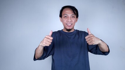Fototapeta premium Young asian man wearing casual shirt giving two thumb up isolated on white backgroudn while looking at the camera