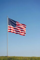 Obraz premium USA Flag on Flagpole in Open Field Under Blue Sky Minimal Patriotic Scene