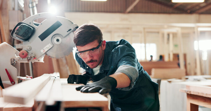 Man, carpenter and miter saw for wood at workshop with manufacturing process at industrial plant. Person, power tools and technician with equipment for cutting, material and safety goggles at factory