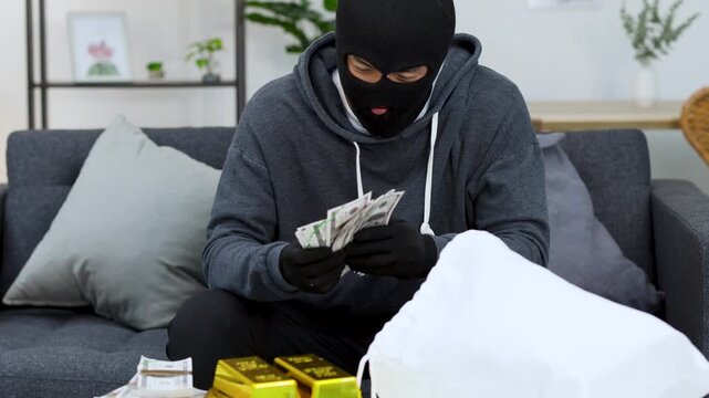 Masked Burglar Removing Ski Mask While Counting Stolen Cash and Gold