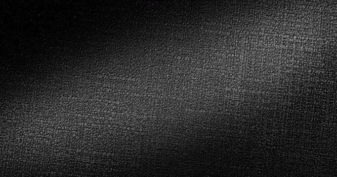 Black Texture Abstract. Slow smooth rotation of dark textured surface with fine grain pattern gently moving under dramatic directional light creating subtle highlights and deep shadows.