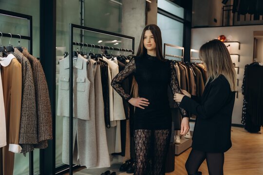 Personal stylist helping young woman choosing fashion dress