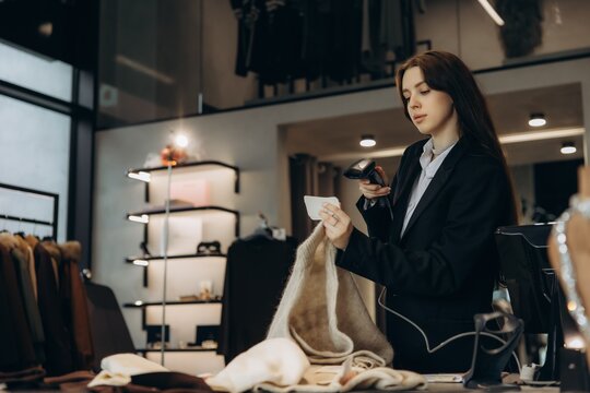 Saleswoman scanning barcode on clothing item in boutique