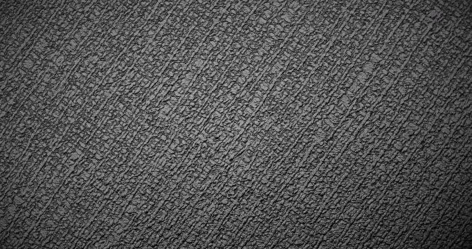 Seamless Abstract black texture. Slow, smooth loop rotation of a dark, rough surface, gently rotating under the light, creating subtle highlights.