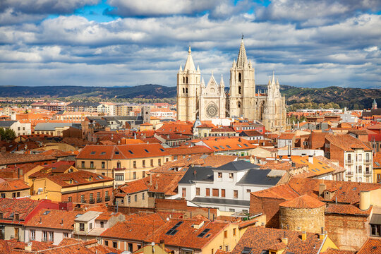 Elevated view of Leon skyline with the Gothic Santa Maria de Regla Cathedral. Historic cityscape with terracotta tiled roofs under a cloudy blue sky in Castile and Leon, Spain.