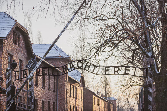 OSWIECIM, POLAND - JANUARY 5, 2025: The Arbeit Macht Frei entrance gate at the Auschwitz I Nazi concentration camp memorial and museum under a light dusting of snow during winter.